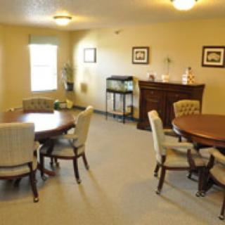 A cozy dining room with round tables and upholstered chairs.