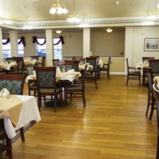 An empty dining room with neatly arranged tables and wooden flooring.