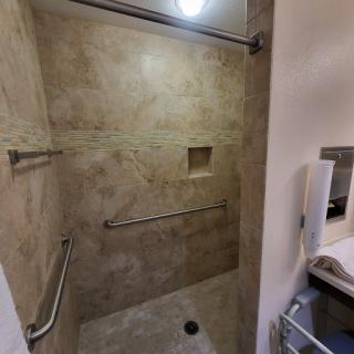 A spacious, modern shower area featuring tiled walls and accessibility bars.