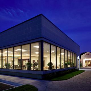 A modern glass-fronted building is illuminated at night, showcasing its sleek architectural design.