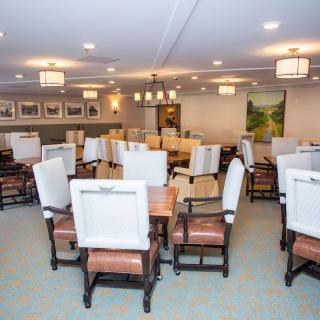 An elegantly arranged dining room with tables and chairs, well-lit and decorated with artwork on the walls.