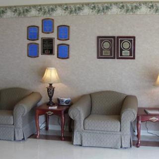 A cozy living room with armchairs, lamps, and decorative wall plaques.