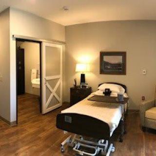 A well-furnished hospital room featuring a bed and cozy amenities.