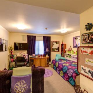 A cozy, colorful bedroom with a variety of decor, including artwork on the walls and patterned bedding.
