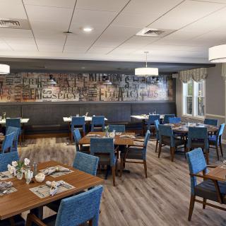 A modern dining area with blue upholstered chairs and wooden tables, featuring stylish lighting and decor.