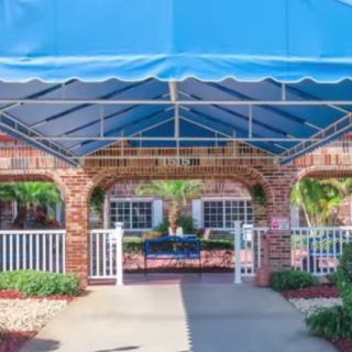 An outdoor area featuring a brick archway with a blue canopy, surrounded by gardens.