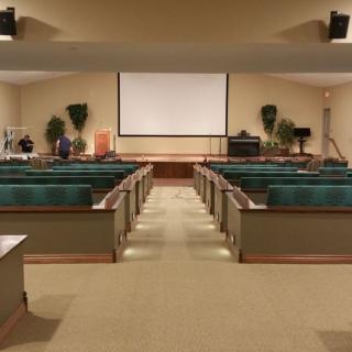An empty auditorium with rows of seats facing a large projector screen.