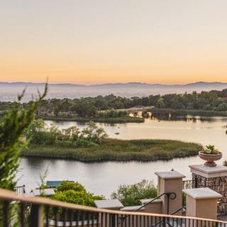 A tranquil lake view at sunset, surrounded by lush greenery and picturesque scenery.