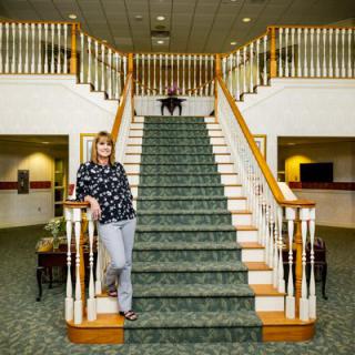 Two people in a hotel lobby with a grand staircase.