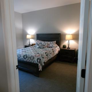 A cozy and well-decorated bedroom featuring a neatly made bed, stylish nightstands, and warm lighting.