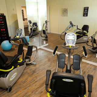 A modern gym equipped with stationary bikes and an exercise ball, featuring mirrored walls.