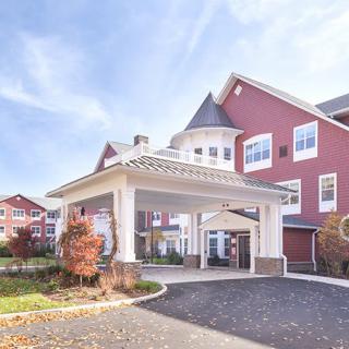 A picturesque residential building with a welcoming entrance and vibrant red exterior under a clear blue sky.