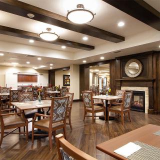 A modern dining room with neatly arranged tables and chairs, featuring elegant lighting and a cozy atmosphere.