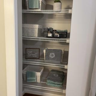 A neatly organized closet with shelves filled with storage baskets and home decor items.
