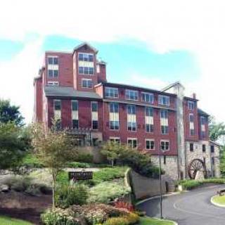 A red brick multi-story building surrounded by landscaped greenery under a clear sky.