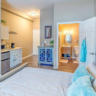 A modern bedroom with neutral colors, featuring an open bathroom design and stylish furniture.