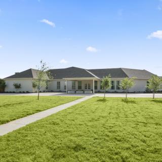 A spacious house with a well-maintained lawn under a clear blue sky.
