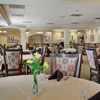 An elegant restaurant dining area with neatly arranged tables and chairs, adorned with floral centerpieces.