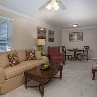A cozy living room with a sofa, armchair, and coffee table adjacent to a small dining area.