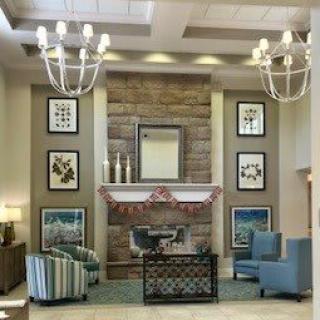 A modern and cozy living room interior with a stone fireplace, comfortable seating, and elegant chandeliers.