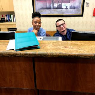 Two cheerful receptionists at the front desk, ready to assist visitors.