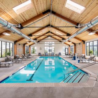 Spacious indoor swimming pool area with wooden ceiling beams and ample natural light.
