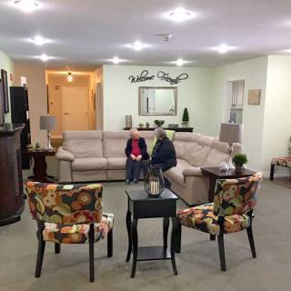 Two people sitting in a cozy living room with comfortable seating and warm lighting.