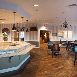 A cozy restaurant interior featuring a bar counter, dining tables, and warm lighting.