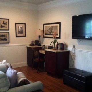 A cozy living room featuring a mounted television, artwork on the walls, and comfortable seating.