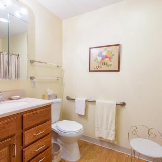 A clean and bright bathroom with a wooden cabinet, a toilet, and towels neatly arranged.
