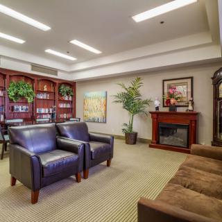 A cozy living room with comfortable seating, a fireplace, and a fully stocked bookshelf.