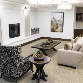 A modern living room with a sofa, patterned chair, coffee table, and fireplace.