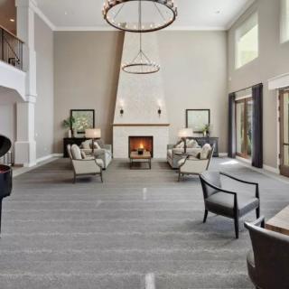 A spacious and modern living room with a grand fireplace and elegant chandelier.