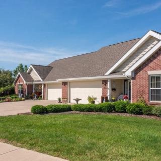 A suburban brick house with a well-maintained lawn and driveway.
