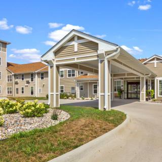 A modern residential building with a covered entrance and landscaped surroundings.