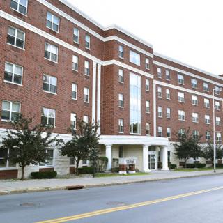 A modern brick residential building with multiple windows and a welcoming entrance.