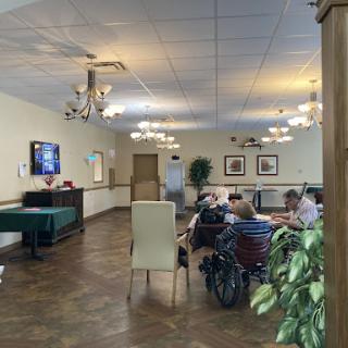 A cozy activity room in a senior center, featuring a pool table and people engaging in conversation.