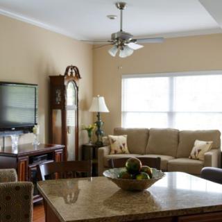A cozy living room with a sofa, television, and coffee table under a ceiling fan.