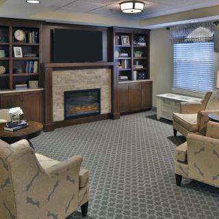 A cozy living room featuring a fireplace, bookshelves, and comfortable seating.