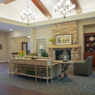 A cozy living room featuring a stone fireplace, chandeliers, and comfortable seating.