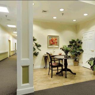 A well-decorated hallway with a small table and chairs, surrounded by plants and artwork.