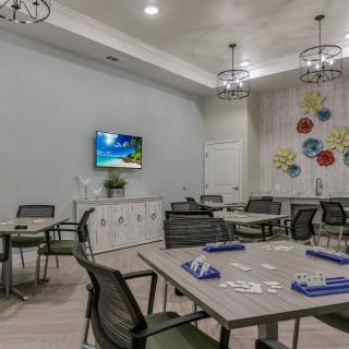 A modern dining room with several tables and chairs, featuring decorative light fixtures, wall art, and a television.