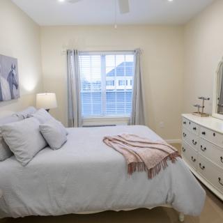 A cozy, well-lit bedroom featuring a comfortable bed and a dresser.