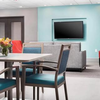A modern lounge area featuring comfortable seating, a television, and a table with chairs.