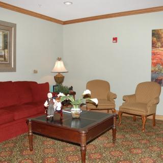 A cozy living room with a red sofa, two armchairs, and a coffee table adorned with decorative items.