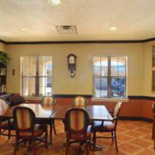 A cozy dining area with wooden tables and chairs, featuring large windows and a wall clock.