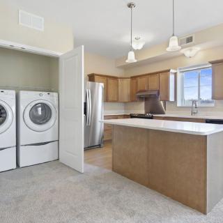 A modern kitchen with an island and adjacent laundry area.