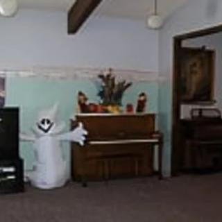 A cozy living room with a piano, TV, and Halloween decorations featuring an inflatable ghost.