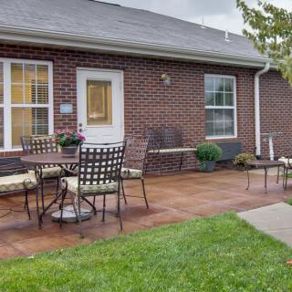 A cozy patio with outdoor furniture in front of a brick house.