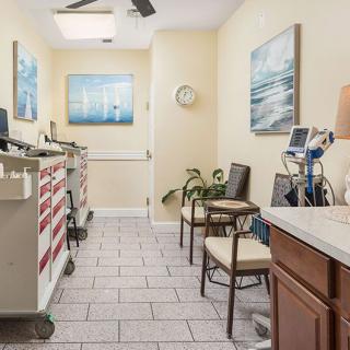 A small medical office waiting area with chairs, medical equipment, and artwork on the walls.